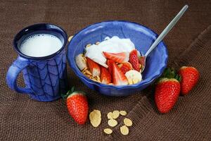 sano desayuno. copos de maíz, Fresco fresas, banana, yogur y Leche foto