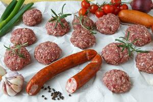 Raw minced hamburger meat and sausage with herb and spice prepared for grilling photo