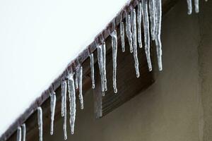 Icicles which are hanging down from a roof photo