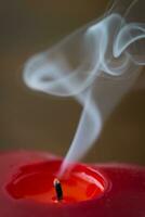 Extinguished red candle with smoke photo
