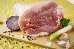 Raw knuckle of pork on wooden cutting board with garlic photo