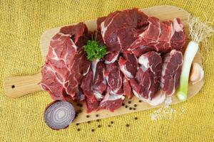 Raw beef on wooden board with garlic and onions photo