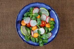 Bowl of fresh vegetable salad on jute table cloth photo
