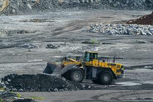 Front loader with large wheels and steel chains. Opencast mining quarry with machinery and mining equipment. Limestone mining for cement production. photo