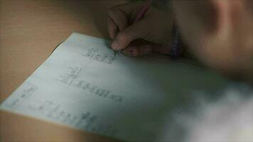 Girl writing notebook during school lesson, doing homework exercise, education. Clip. Little girl draws a pen on sheet of paper video