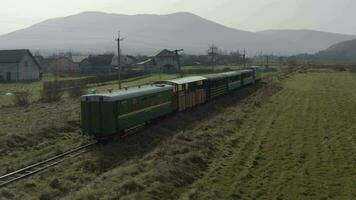 Antenne Aussicht von das Zug Fahrten auf das Eisenbahn. Drohne Flug Über das Lokomotive und Wagen von das eng Spur Eisenbahn. video