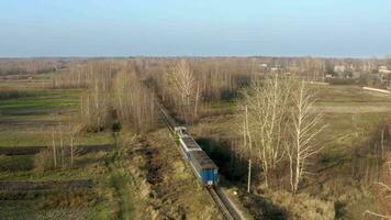 Aerial view of A locomotive and two carriages move along a narrow gauge railway in the countryside. video