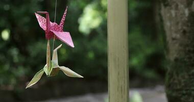 A paper crane swaying in the wind at the traditional street close up handheld video