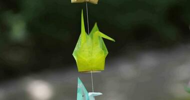 A paper crane swaying in the wind at the traditional street close up handheld video