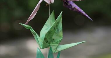 A paper crane swaying in the wind at the traditional street close up handheld video