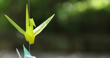 A paper crane swaying in the wind at the traditional street close up handheld video