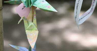 A paper crane swaying in the wind at the traditional street close up handheld video