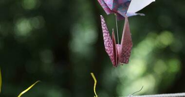 A paper crane swaying in the wind at the traditional street close up handheld video