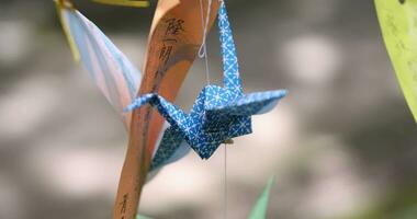 A paper crane swaying in the wind at the traditional street close up handheld video