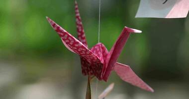 A paper crane swaying in the wind at the traditional street close up handheld video