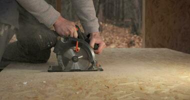 de cerca de un trabajador utilizando un circular Sierra a cortar madera contrachapada. construcción de un nuevo de madera casa utilizando marco tecnología. video