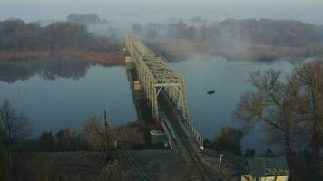 aéreo ver de el ferrocarril puente terminado el río en el niebla en el temprano Mañana video