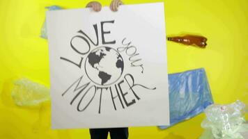 Girl activist holding poster Love Your Mother Earth. Plastic nature pollution video