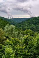 verde Valle cubierto con bosque y en el horizonte son el enfriamiento torres de un nuclear poder planta dukovany. contraste de naturaleza y industria. checo república. foto