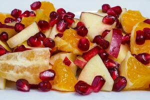 Delicious fruit salad with fresh fruit. Pomegranate, orange, apple photo