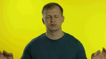 Portrait of young man posing in t-shirt. Exhausted handsome guy meditates and breathes deeply video