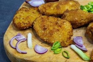 Fried chicken schnitzel on a cutting board. Homemade breaded schnitzel. Fried crispy chicken legs. photo