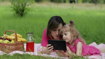 familie weekend picknick. dochter kind meisje met moeder studie lessen Aan tablet. afstand onderwijs video