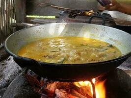 el proceso de Cocinando rendang o carne de vaca y pollo curry utilizando el tradicional método, Cocinando utilizando leña foto