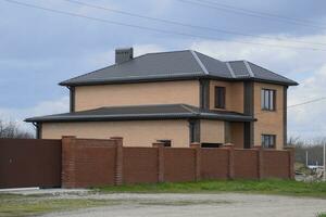 house is of pink brick and roof of metal is brown. photo