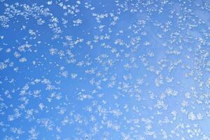 Abstract winter background. Frost on a frozen window against the blue sky. photo