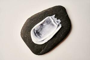A smear of white cream on a black stone. photo