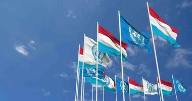 Luxembourg et uni nations, ONU drapeaux agitant ensemble dans le ciel, sans couture boucle dans vent, espace sur la gauche côté pour conception ou information, 3d le rendu video