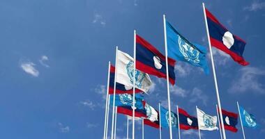 Laos and United Nations, UN Flags Waving Together in the Sky, Seamless Loop in Wind, Space on Left Side for Design or Information, 3D Rendering video