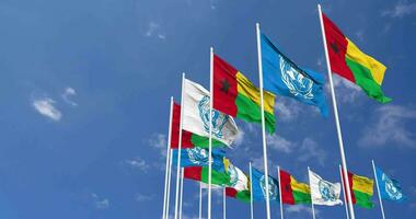 Guinea Bissau y unido naciones, Naciones Unidas banderas ondulación juntos en el cielo, sin costura lazo en viento, espacio en izquierda lado para diseño o información, 3d representación video