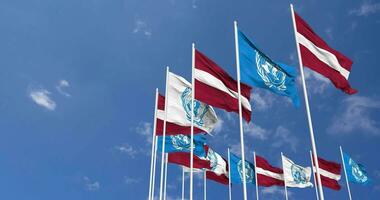 Latvia and United Nations, UN Flags Waving Together in the Sky, Seamless Loop in Wind, Space on Left Side for Design or Information, 3D Rendering video