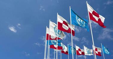 Groenland et uni nations, ONU drapeaux agitant ensemble dans le ciel, sans couture boucle dans vent, espace sur la gauche côté pour conception ou information, 3d le rendu video