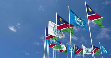 Namibie et uni nations, ONU drapeaux agitant ensemble dans le ciel, sans couture boucle dans vent, espace sur la gauche côté pour conception ou information, 3d le rendu video