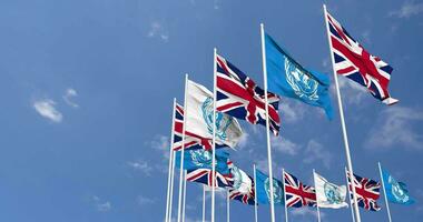 United Kingdom and United Nations, UN Flags Waving Together in the Sky, Seamless Loop in Wind, Space on Left Side for Design or Information, 3D Rendering video