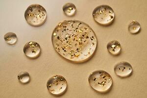 Serum with 24K Gold particles. Drops on a beige background. photo