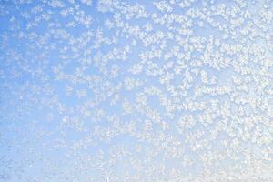 Abstract winter background. Frost on a frozen window against the blue sky. photo