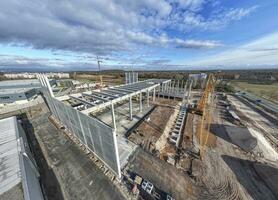 Drone image of a construction site of an industrial building with columns and beams and a heavy-duty crane photo