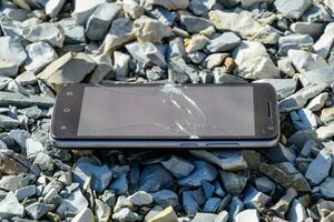 Frustrated phone on the rocks. Glass shattered on rocks on a sma photo