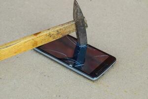 Hammer and smartphone. The screen of the smartphone, a broken ha photo