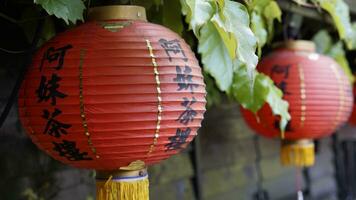 rojo linternas colgando desde un pared con chino escritura foto