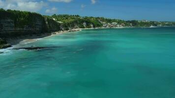 popular turístico playa en bali con surfistas en azul océano. vacaciones en zona tropical. aéreo ver video