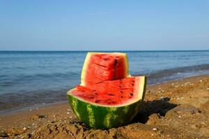 The cut watermelon lies on the seashore. Watermelon in the sea photo