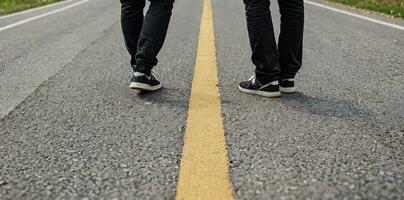 AI generated Two men stand on a road with a yellow median, only the lower parts of their bodies are visible. photo