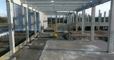 Drone video of a construction site of an industrial building with columns and beams and a heavy-duty crane