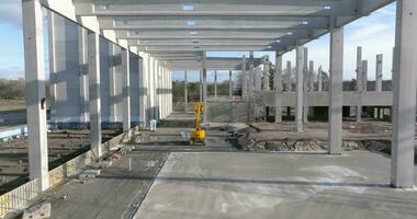 Drone video of a construction site of an industrial building with columns and beams and a heavy-duty crane