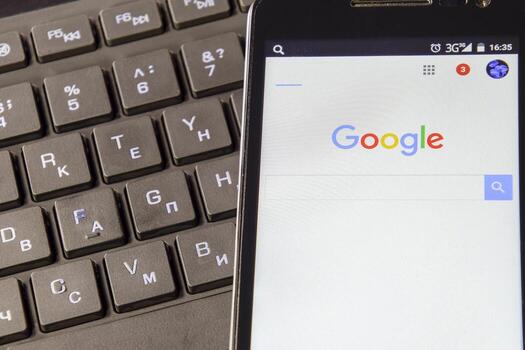 Smartphone with Google search system on the keyboard background. Finding information with the help of Google. photo